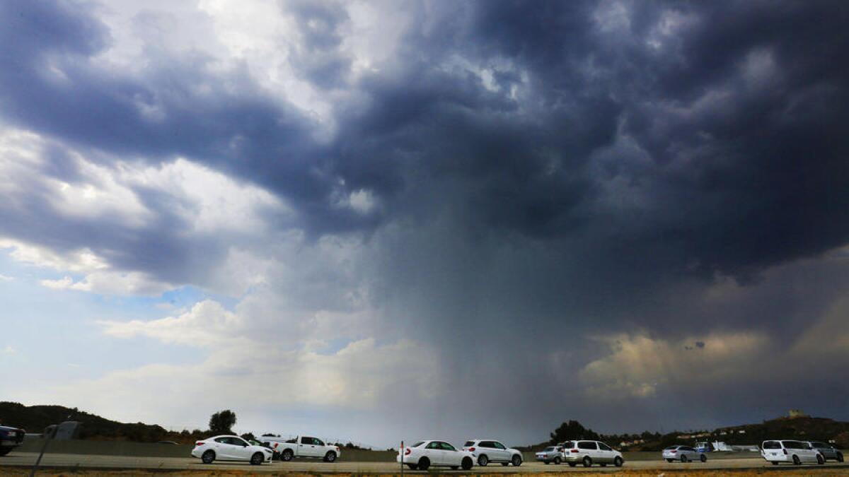 Los autos se mueven lentamente el miércoles a lo largo de la autopista 14 con rumbo al norte en la zona de Santa Clarita, mientras las nubes de tormenta y la lluvia pasan sobre el área.