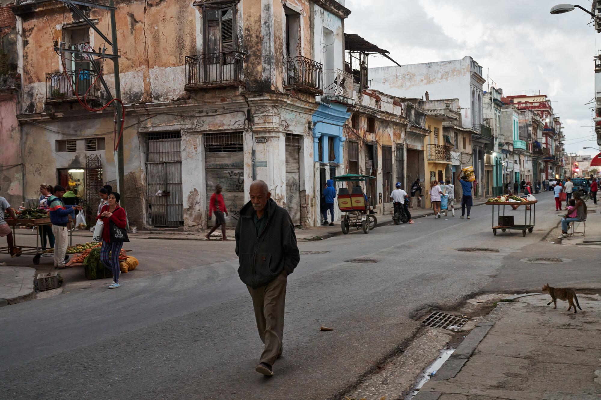 A man walking on a street lined with aging buildings