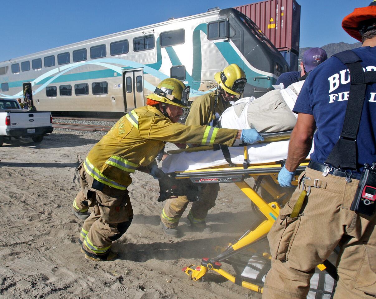 Burbank firefighters load an injured Metrolink passenger to an awaiting ambulance south of the intersection of San Fernando and Buena Vista in Burbank on Monday, September 2, 2014. The southbound train struck a motorist allegedly driving around the downed crossing arms on Buena Vista totalling the vehicle and sending the driver to the hospital with critical injuries. Six people were injured on the train and taken to the hospital.