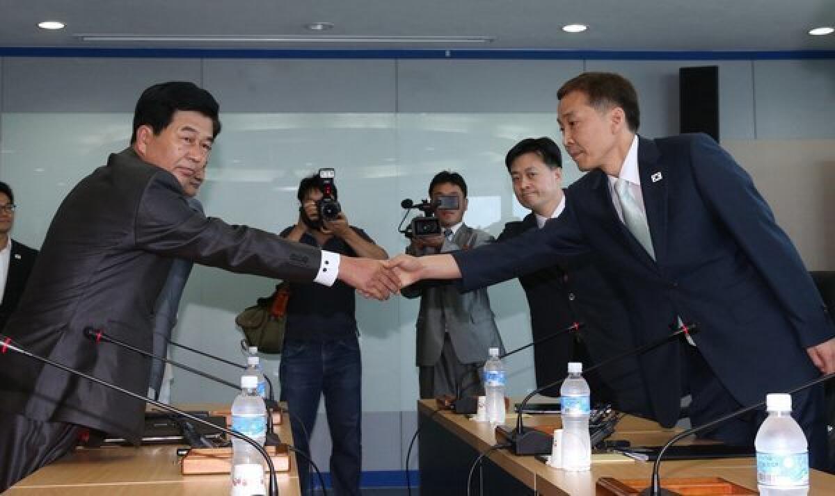 North Korea's chief delegate Pak Chol-su, left, shakes hands with his South Korean counterpart Kim Ki-woong during talks at the Kaesong industrial complex. The two sides reached an agreement on reopening the industrial zone, which was shut down in April amid rising military tensions.