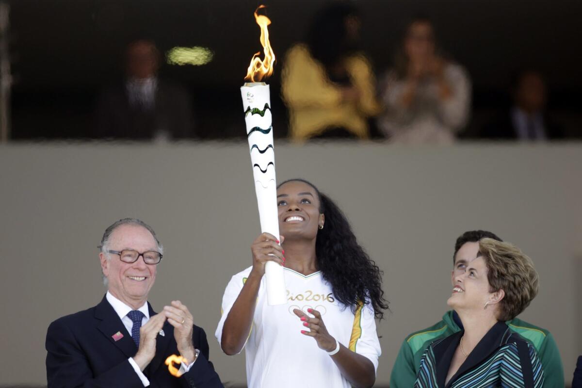 Brazil's Fabiana Claudino, a two-time gold medalist in volleyball, holds the Olympic flame next to Brazilian President Dilma Rousseff, right, and Rio 2016 Organizing Committee President Carlos Nuzman on Tuesday.