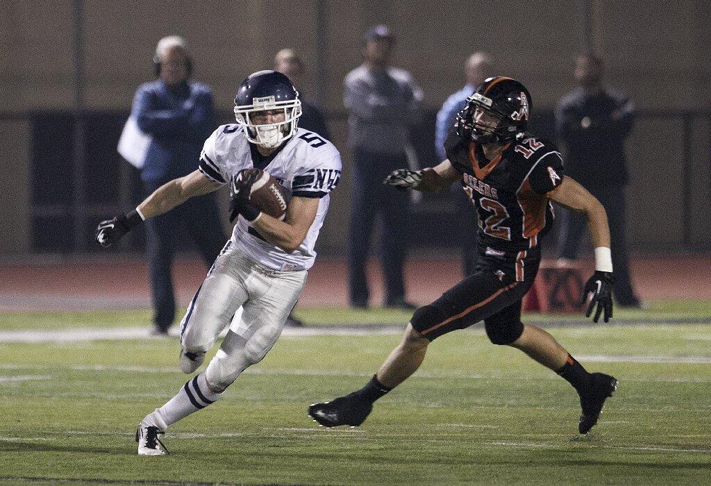 Newport Harbor's Cory Stowell, left, runs upfield as Huntington Beach's Jake Grothjan attempts to track him down during a game at Huntington Beach High School on Friday.