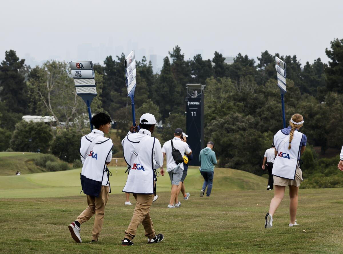 U.S. Open sign bearers walk the 15th fairway during a  practice round at the Los Angeles Country Club.