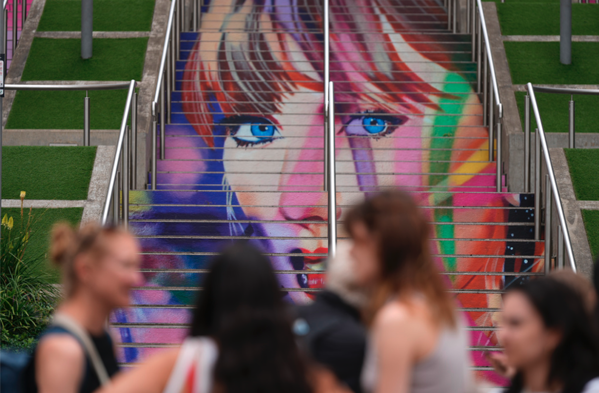 Fans posan junto a un retrato de Taylor Swift 