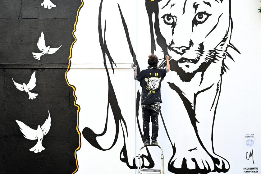 Los Angeles, California, December 20, 2022- Artist Corie Mattie paints a memorial of P-22, the cougar that recently passed away, along Melrose Ave. in Los Angeles Tuesday. (Wally Skalij/Los Angeles Times)