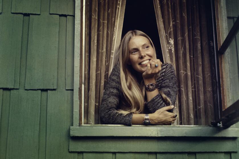 Joni Mitchell, chin in hand, leaning out bedroom window of her home in Laurel Canyon, Oct. 1970