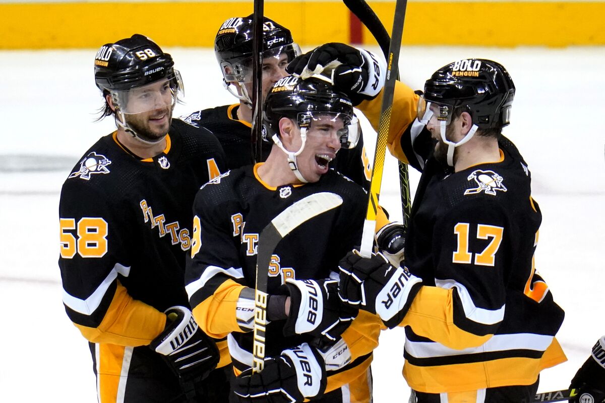 Pittsburgh Penguins' Evan Rodrigues (9) celebrates his hat trick with Bryan Rust (17) during the third period of an NHL hockey game against the San Jose Sharks in Pittsburgh, Sunday, Jan. 2, 2022. Rust also had a hat trick in the game, and the Penguins won 8-5. (AP Photo/Gene J. Puskar)