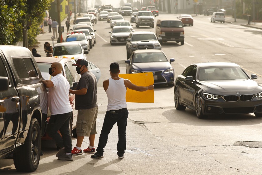 Luis Caciano, right, who has worked for 10 years on the cook line, urges drivers to honk in support of hotel workers.