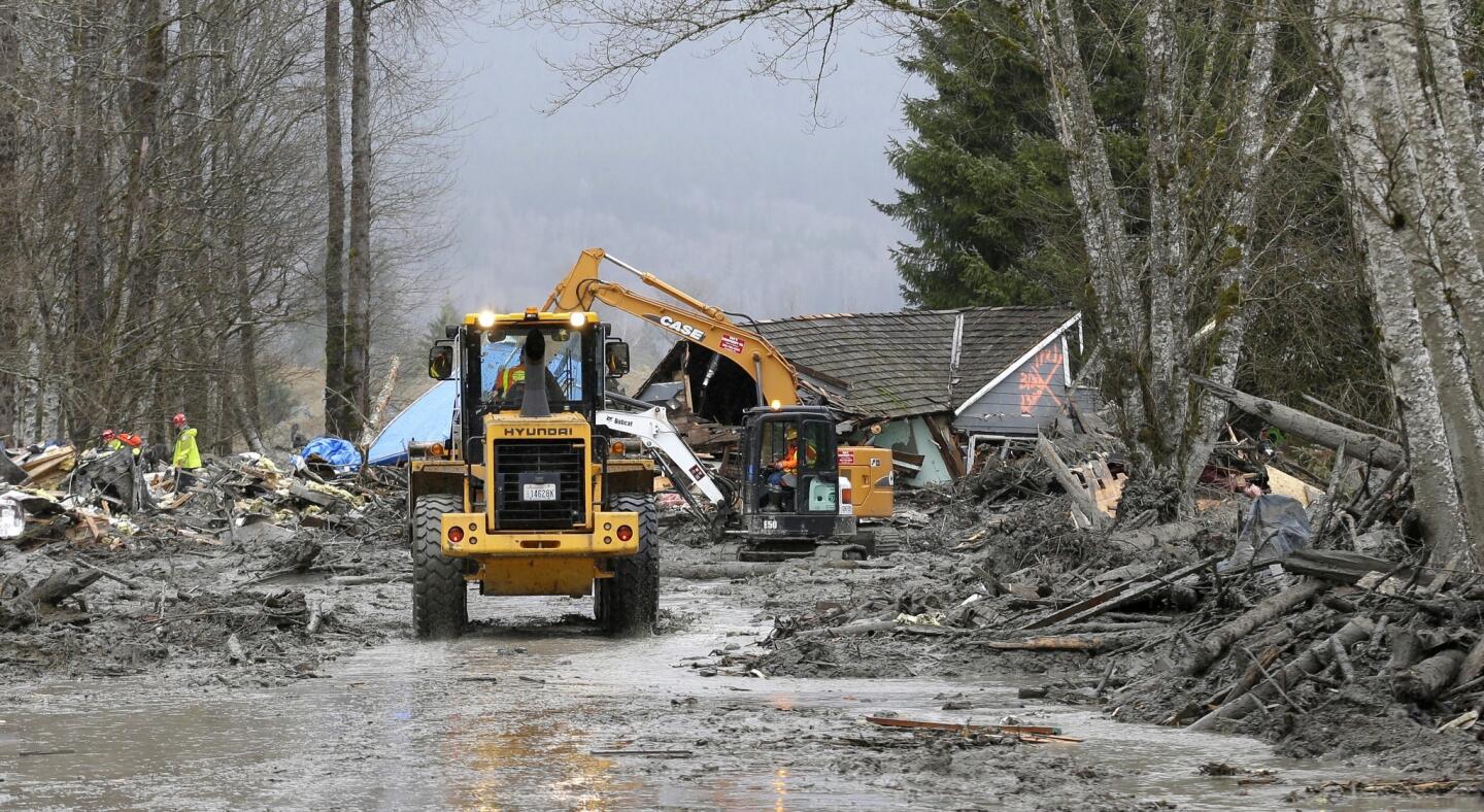 Workers try to clear debris from State Route 530 on the western edge of the massive mudslide.