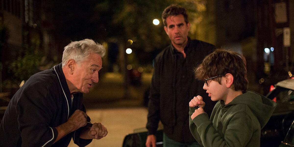 A boy play-fights with his grandpa while his dad looks on in the film "Ezra."