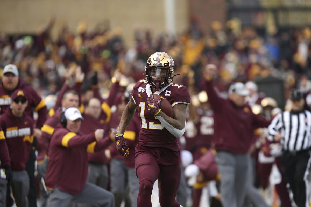 FILE - In this Nov. 9, 2019, file photo, Minnesota wide receiver Rashod Bateman (13) runs the ball down the field for a touchdown against Penn State during an NCAA college football game, in Minneapolis. Bateman initially opted out of the season on Aug. 4, citing concerns about playing amid the coronavirus pandemic, instead signing with an agent and focusing on the NFL draft. But he changed his mind when the Big Ten returned Sept. 16 with daily testing and earned special reinstatement from the NCAA. (AP Photo/Stacy Bengs, File)