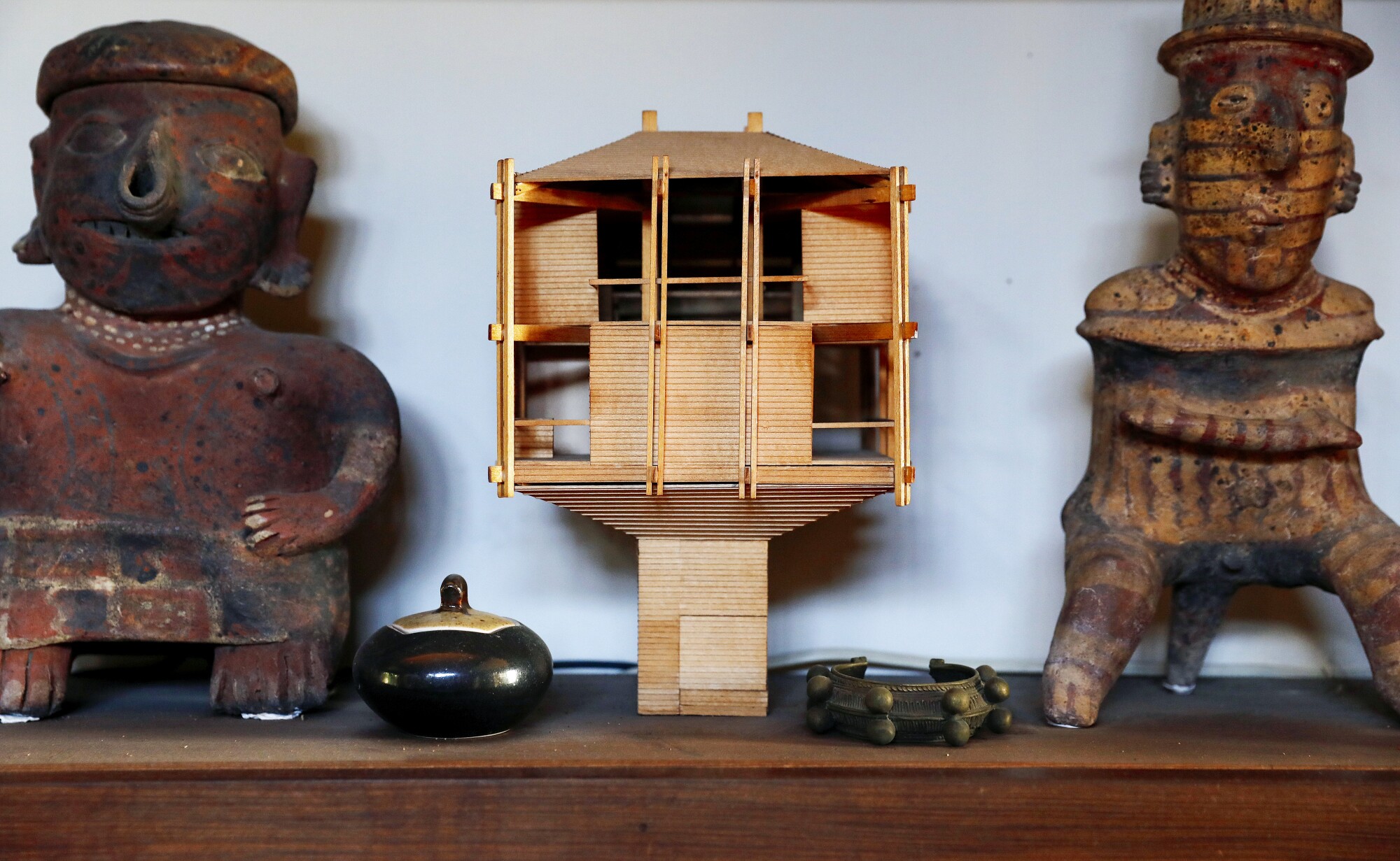 مدل چوبی خانه درختی برنارد قاضی در قفسه ای بین مجسمه های سبک ماقبل کلمبیایی قرار گرفته است.