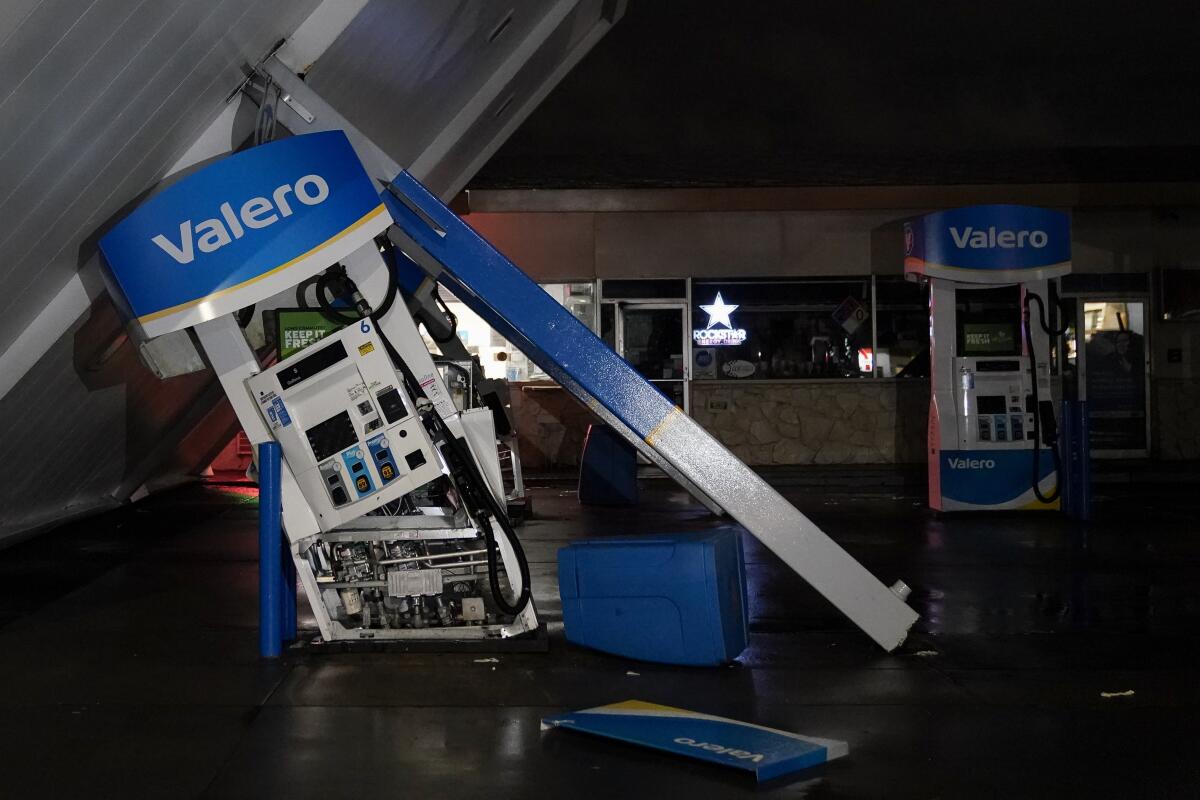 A night image of flash-lighted canopy of gas station, toppled by strong winds, rests at an angle.