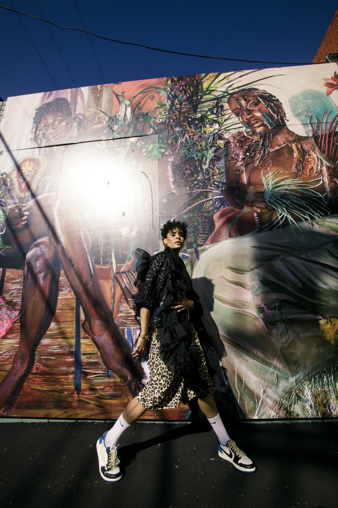 Angela Manuel-Davis poses in front of Gisela McDaniel’s murals outside