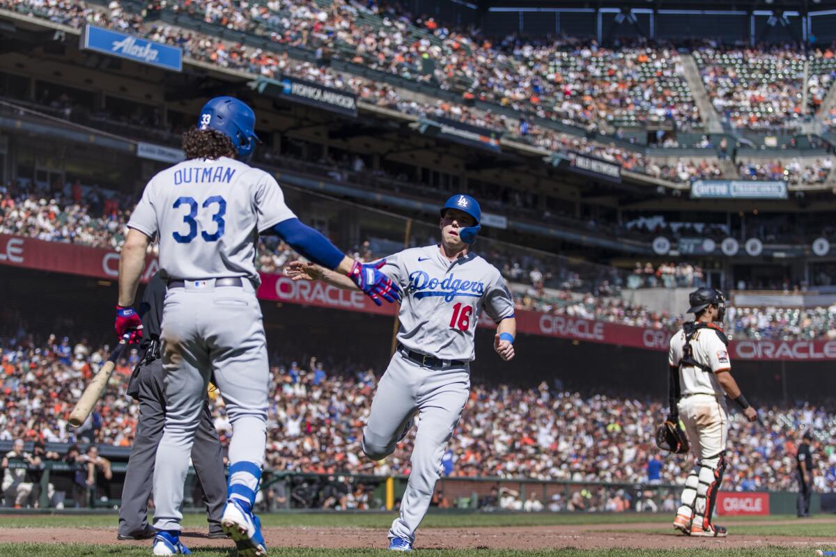Dodgers' Will Smith is congratulated by center fielder James Outman after he scored.