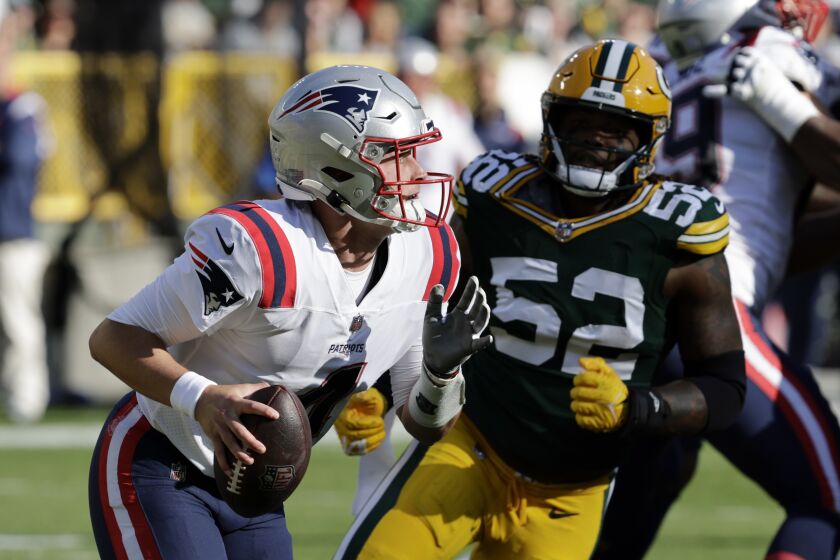 El quarterback de los Patriots de Nueva Inglaterra, Bailey Zappe (4), busca eludir al linebacker de los Packers de Green Bay, Rashan Gary (52), durante la primera mitad del partido de la NFL, en Green Bay, Wisconsin, el domingo 2 de octubre de 2022. (AP Foto/Mike Roemer)