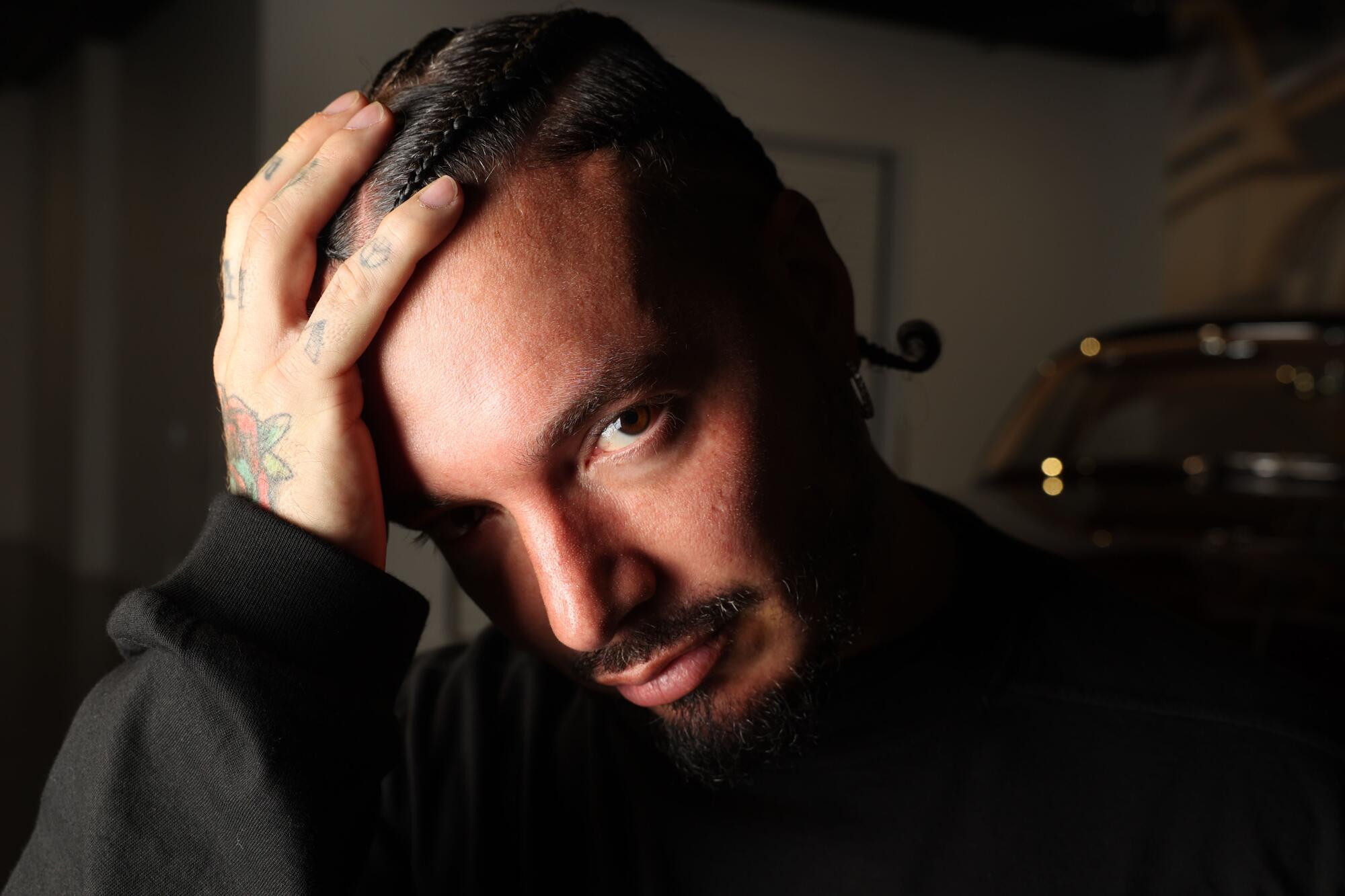 Singer J Balvin holds his head in front of 1953 Cadillac Series 62.