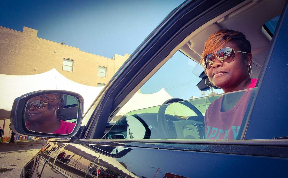 A Black woman looks out her rolled-down car window