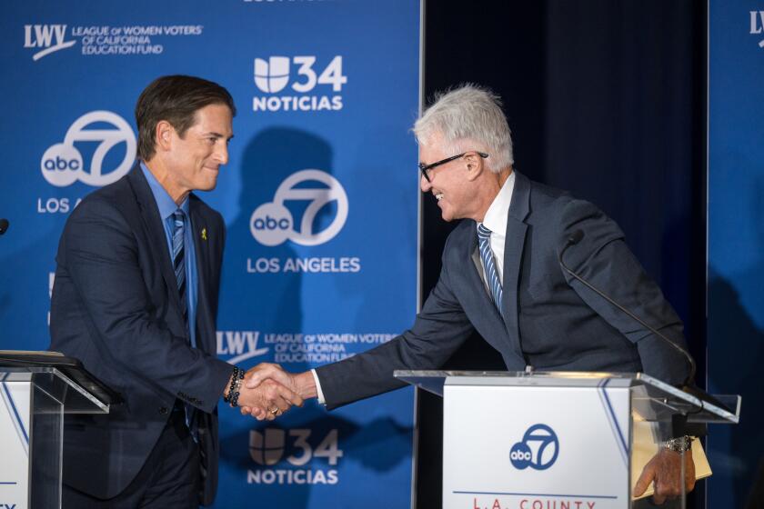 GLENDALE, CA - Sept. 29, 2024: L.A. County District Attorney George Gascon, right, shakes hands with Nathan Hochman during a televised debate in Glendale. (Michael Owen Baker / For The Times)