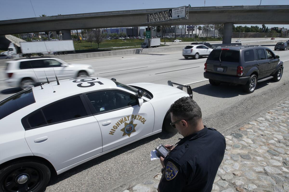 A California Highway Patrol Officer runs a driver's license after stopping a motorist along Interstate 5.