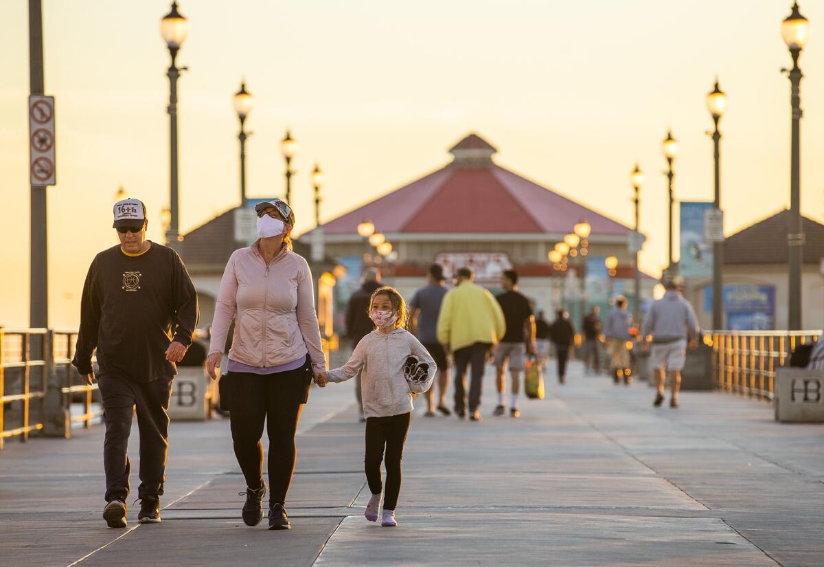 Allan, Allisun and Lilah Gonzalez walk along the Huntington Beach Pier on Monday.