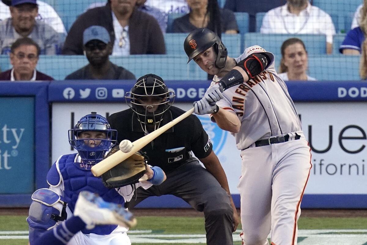 San Francisco Giants Buster Posey, right, hits a two-run home run as Los Angeles Dodgers catcher Will Smith, left, and home plate umpire Jeremie Rehak watch during the first inning of a baseball game Monday, July 19, 2021, in Los Angeles. (AP Photo/Mark J. Terrill)