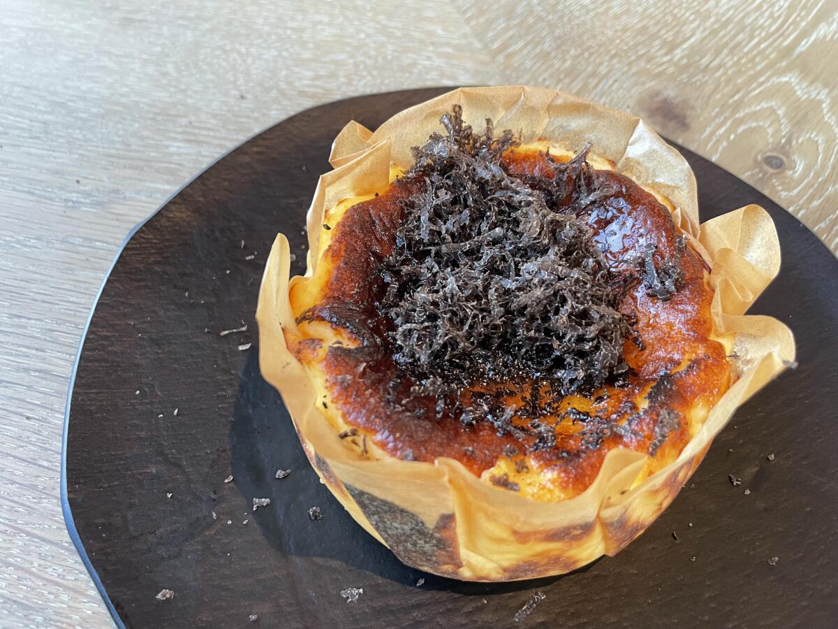 Cheesecake served in baking paper with mounded, shaved truffle on top.