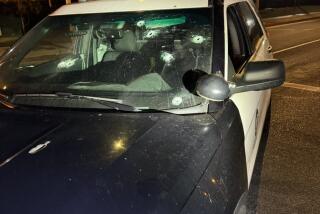 A police cruiser with bullet holes in the front windshield.