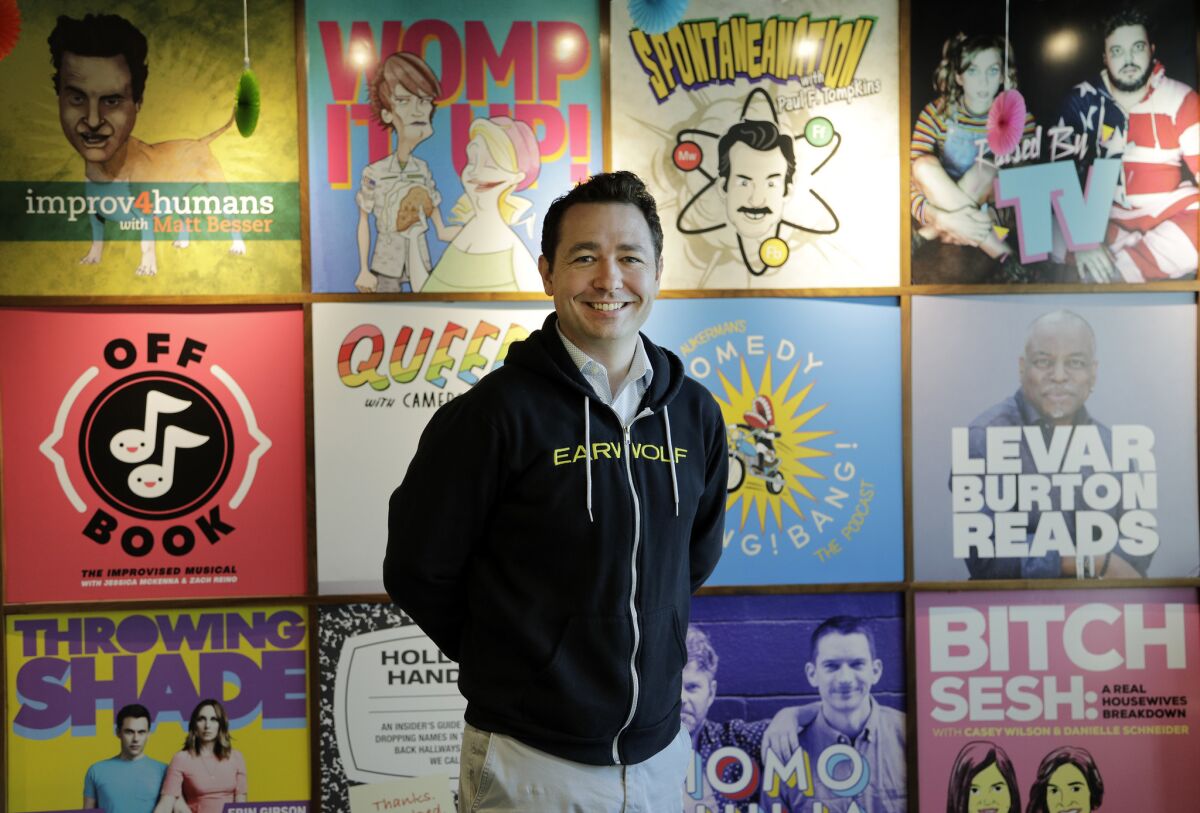 Colin Anderson is executive producer at comedy podcasting network "Earwolf." Behind him are posters of the various podcasts. The company has expanded to include big-name talents including Conan O'Brien.