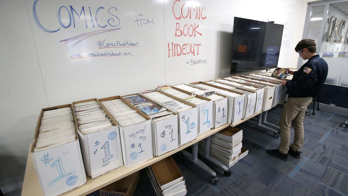 A student sifts through boxes of dollar comic books at the first Fan Con at the Laguna Beach High School library Thursday.