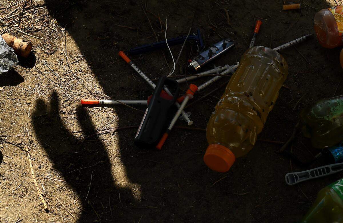 A shadow of a work crew member stands over syringes and other items. 