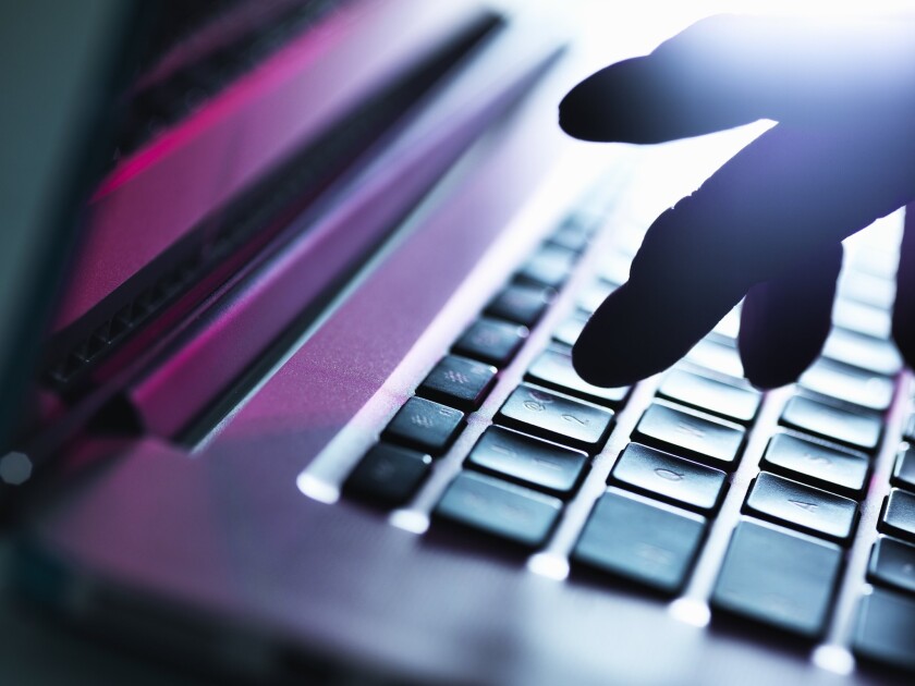 Silhouette of a male hand typing on a keyboard