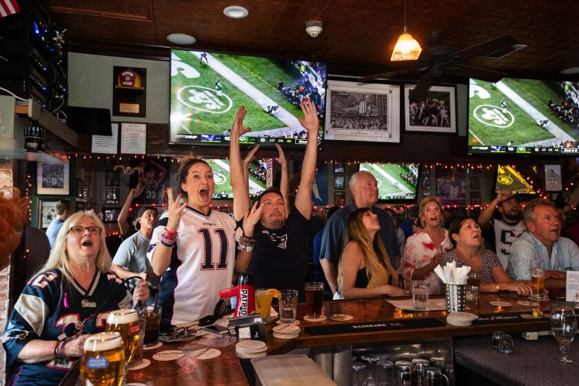 Sports fans and bargoers react to a touchdown by the New England Patriots against the New York Jets.