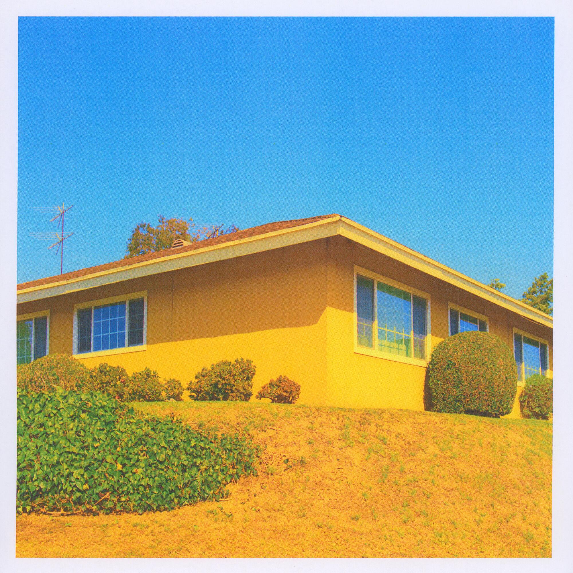 A photo of a yellow house against a blue sky.