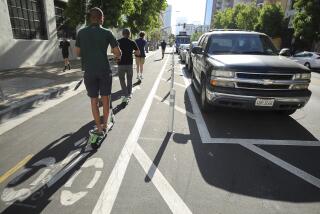 People riding electric scooters use a bike lane next to where cars park away from the curb on J Street, near the Eleventh Avenue intersection in downtown on Tuesday, July 9, 2019 in San Diego, California.