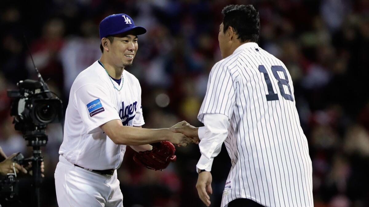 Former pitcher Hiroki Kuroda shakes hands with Pitcher Kenta Maeda of the Dodgers after throwing a ceremonial first pitch prior to the Game 4 between Japan and MLB All Stars.