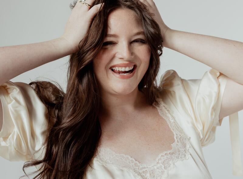 A woman plays with her hair while posing for a photo