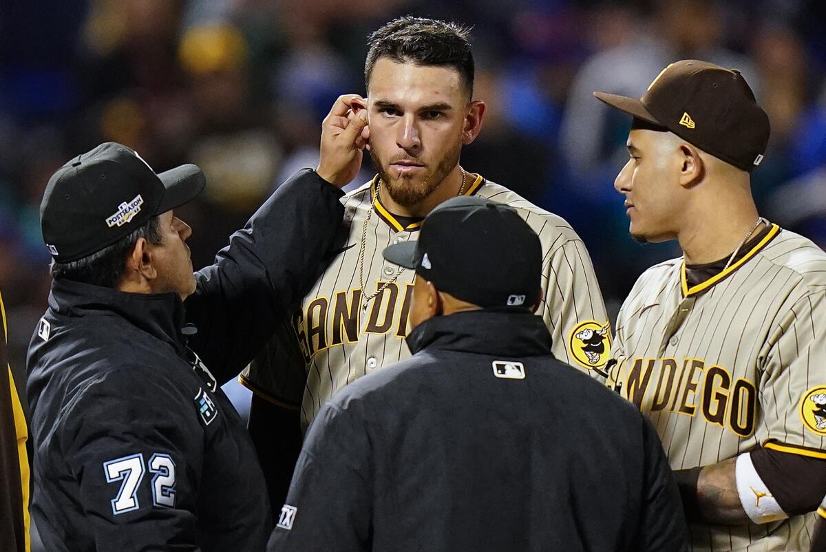 Umpire Alfonso Marquez checks for substances behind the ear of San Diego Padres starting pitcher Joe Musgrove
