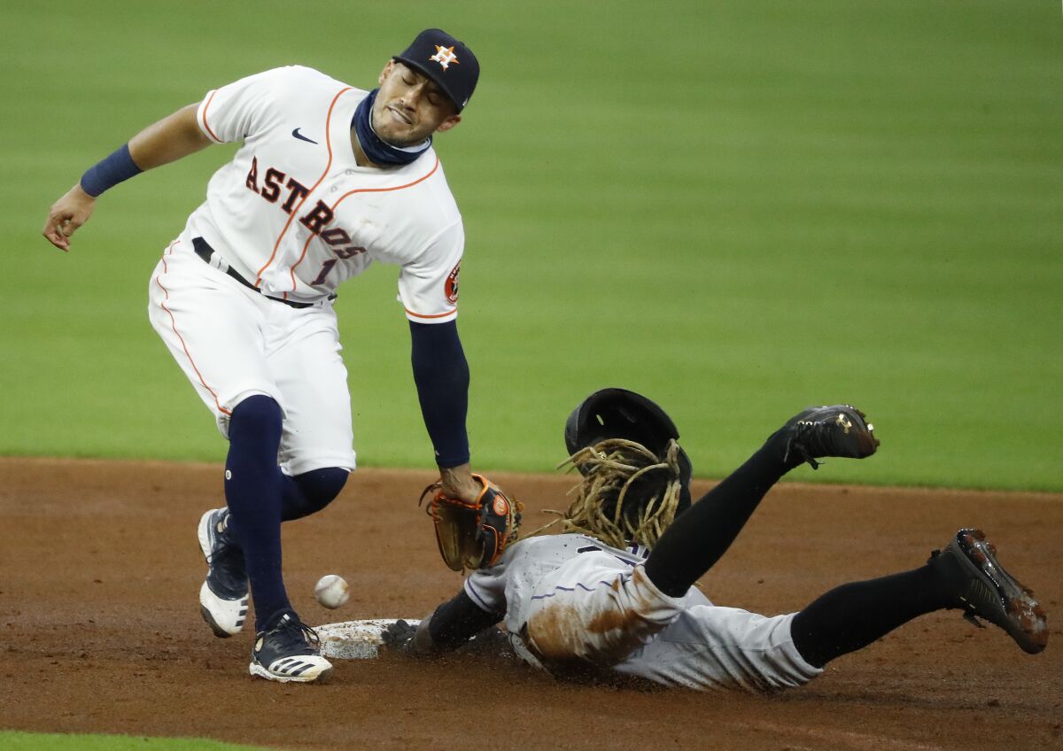 Houston Astros shortstop Carlos Correa can't contain a throwing error from catcher Dustin Garneau as the Colorado Rockies' Raimel Tapia steals second base in the top of the second inning on Monday, Aug. 17, 2020, in Houston. (Kevin M. Cox/The Galveston County Daily News via AP)