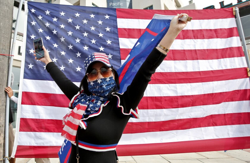 President Donald Trump supporter Kim Nguyen of Corona stands in front of an American flag.