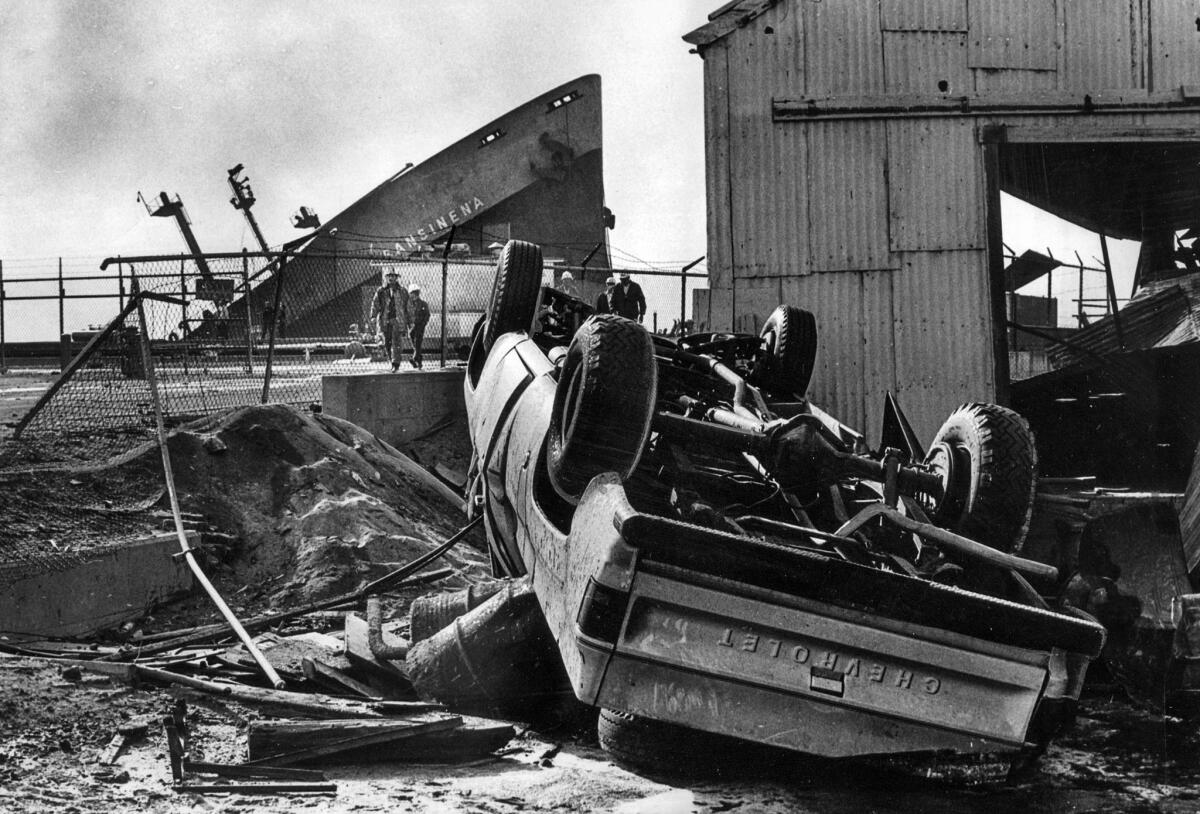 Dec. 18, 1976: An truck overturned by the explosion of the tanker Sansinena, whose bow juts skyward in background.