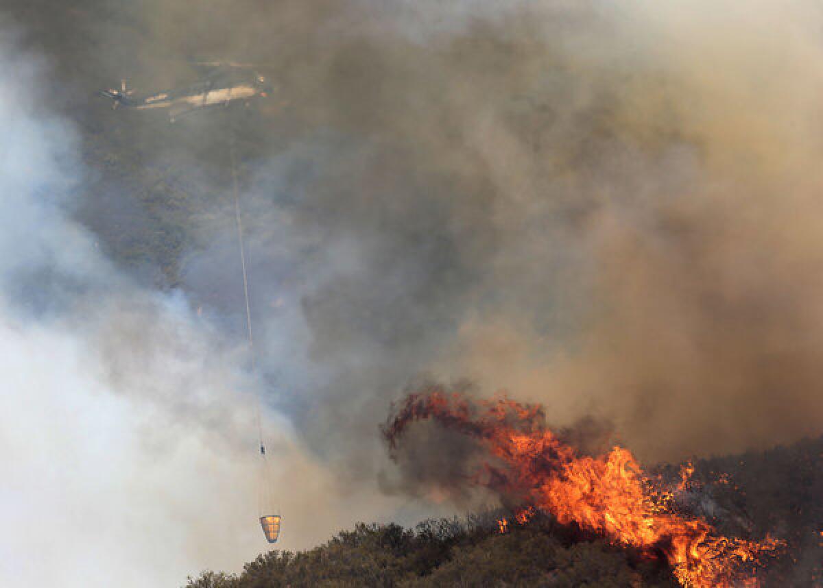 A water-dropping helicopter hovers above the Powerhouse Fire on Friday.