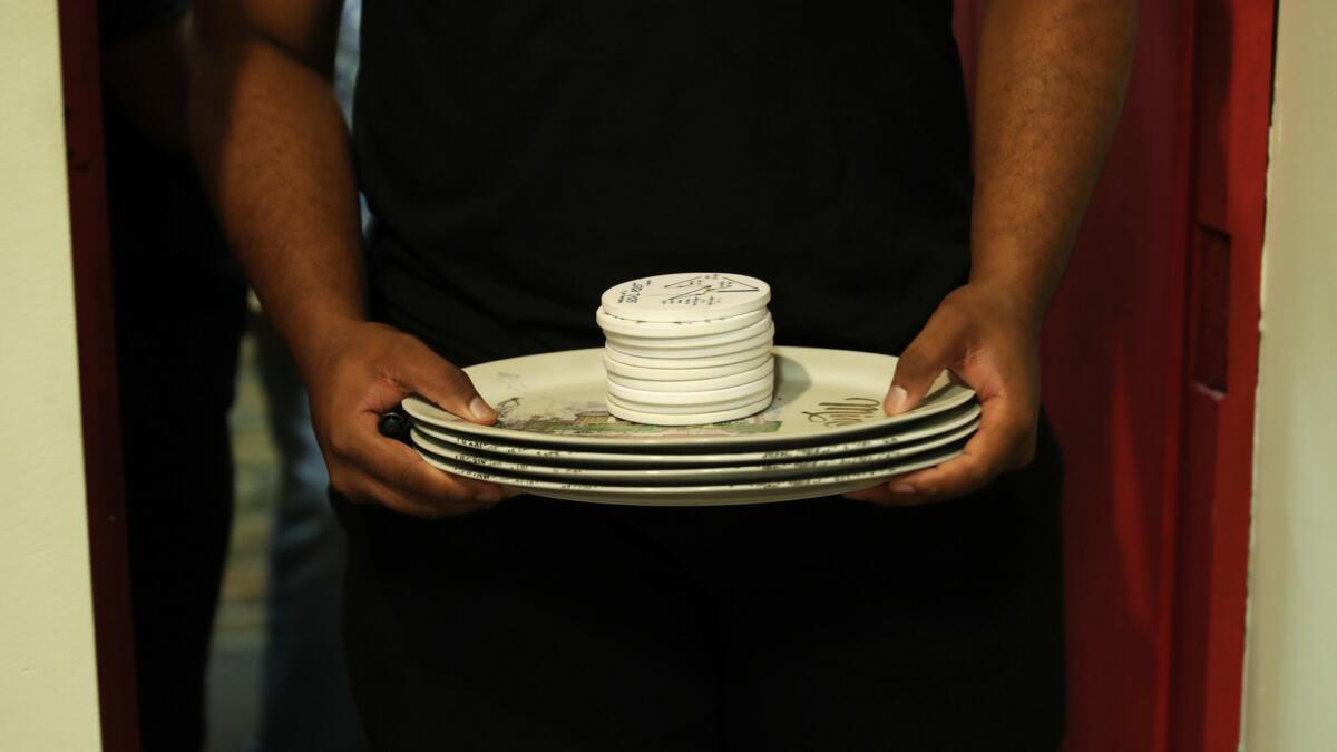Manager Roosevelt McMullan carries plates and ceramic discs picked for destruction Aug. 24, 2018, at the Escapades Chicago Escape and Rage Room in Chicago's River North neighborhood.