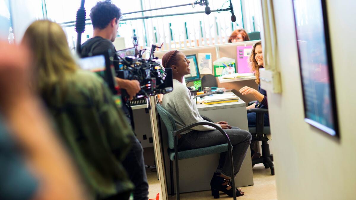 Actress Issa Rae, seated at left, between scenes, with actress Lisa Joyce on the set of HBO's second season of "Insecure."