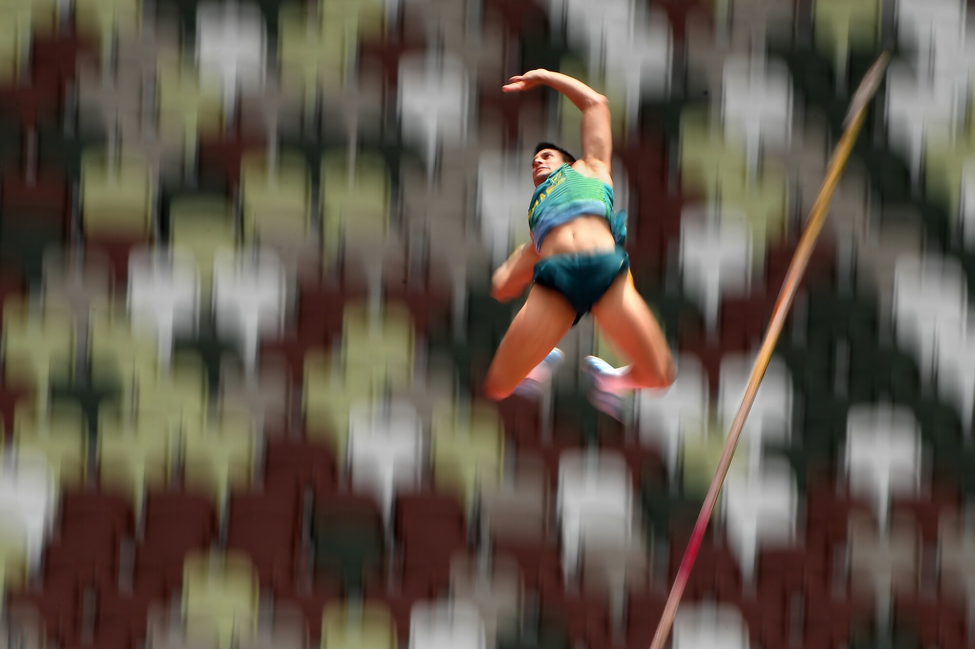 A man falls after clearing the pole vaulting bar.