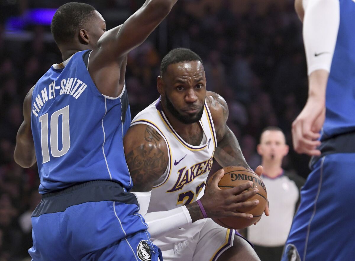 Lakers star LeBron James drives to the basket in front of Dallas Mavericks forward Dorian Finney-Smith, left, during the first half of the Lakers' 108-95 win Sunday at Staples Center.
