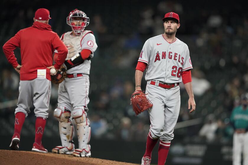 The Angels' Andrew Heaney, right, walks off the mound after being pulled by manager Joe Maddon, left. Kurt Suzuki looks on.