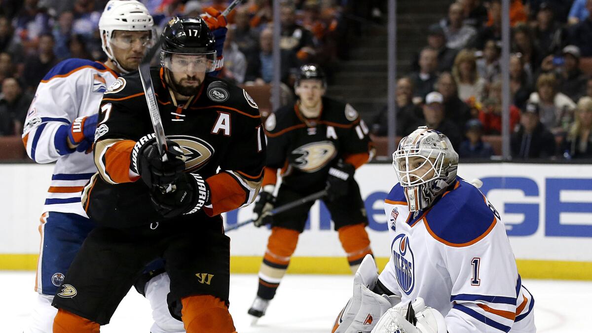 Ducks center Ryan Kesler, center, keeps his eyes on the airborne puck that rebounded off Oilers goalie Laurent Brossoit (1) during the second period Wednesday night.