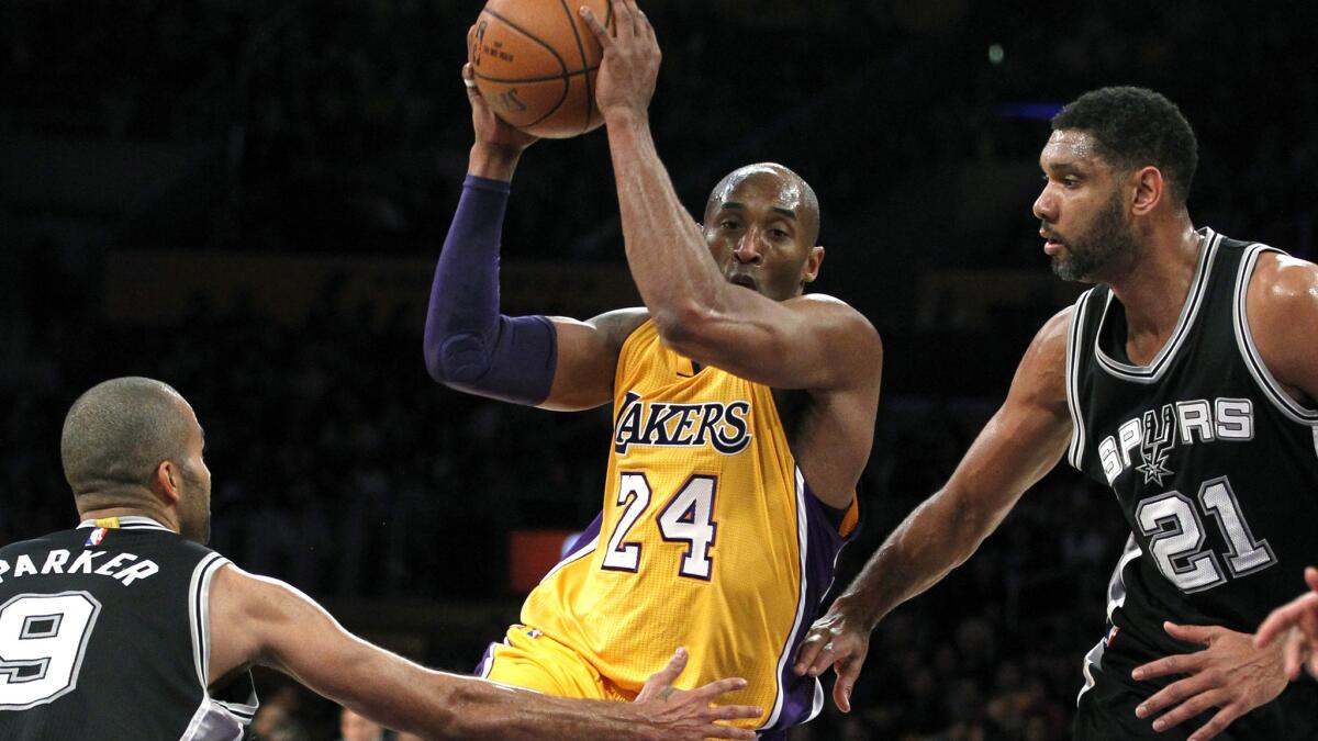 Lakers forward Kobe Bryant (24) drives the lane against Spurs guard Tony Parker (9) and center Tim Duncan (21) during the first half.