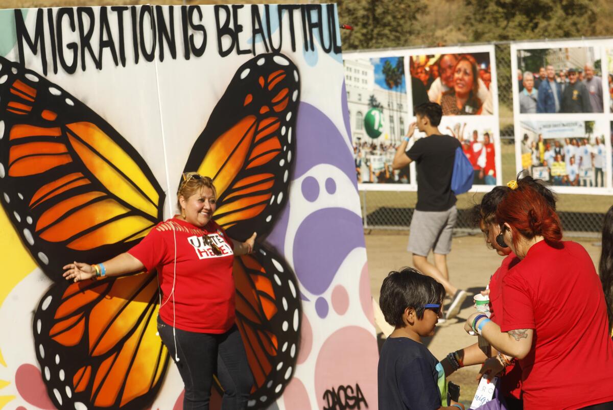 Claudia Aguilera, left, waits to have her picture made where art and photographs from the early 90s were on display at the, “Rally for Justice Immigrant Rights and Equality - 25 years beyond Proposition 187,” at the Los Angeles State Historic Park.